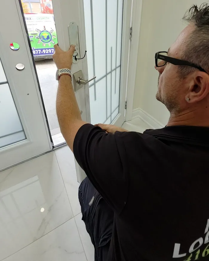 Matrix locksmith fitting new lever hardware on a white entry door